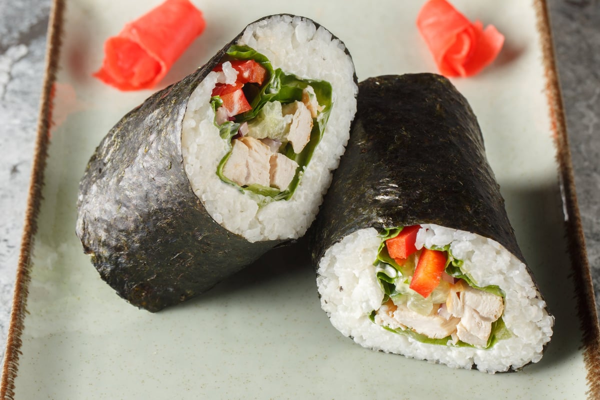 Sushirrito with rice, chicken breast, cream cheese, vegetables, nori and lettuce close-up